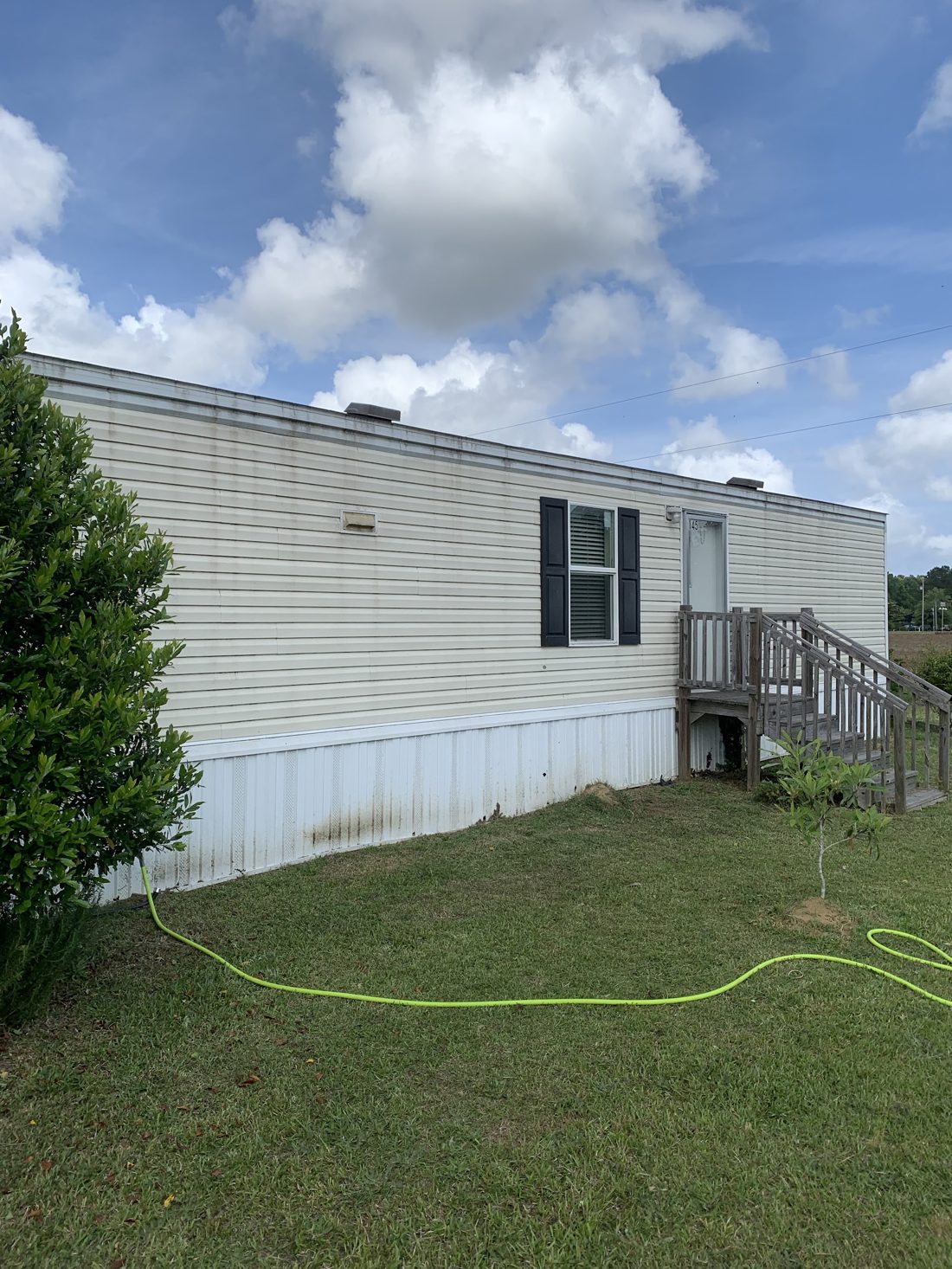 Long wall of washed siding with steps and a lawn