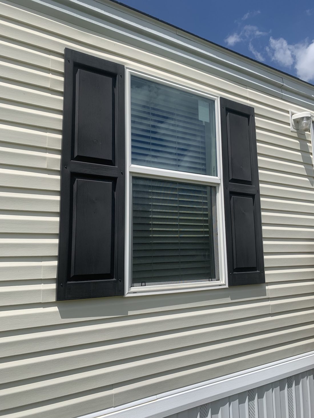 Cleaned vinyl siding around a window with black shutters